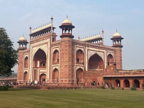Red sandstone gateway structure with tourists.