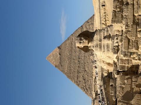       The Great Sphinx and Pyramid in Cairo under a blue sky.
  