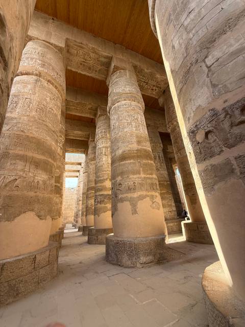       Ancient columns with detailed carvings inside a temple.
  