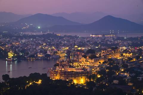 Cityscape of Udaipur at twilight with palace and lakes.