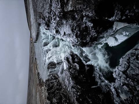       Icy waterfall flowing through a rocky landscape.
  
