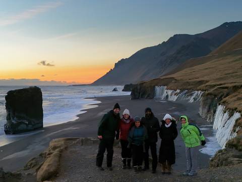 Group standing on a coastline during sunset.