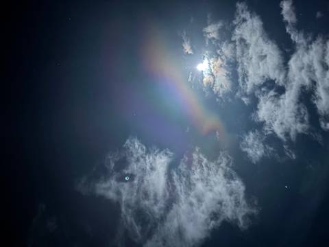 Rainbow among clouds with a bright moon.