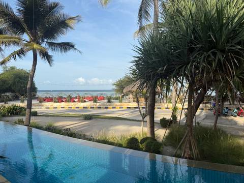 View of a beachside resort area with palm trees and beach chairs.