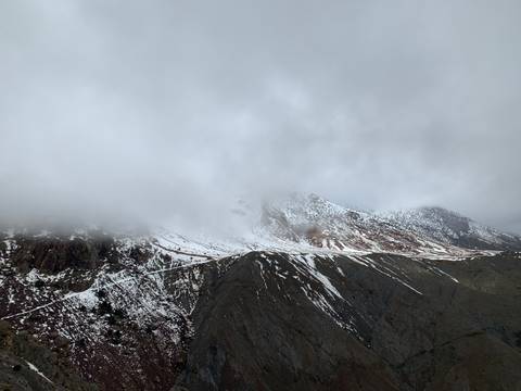 Snow-capped mountain partially covered in clouds.