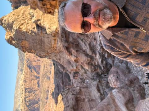 Man posing with rugged desert landscape in the backdrop.