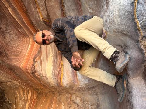 Person sitting inside a cave with colorful rock formations.
