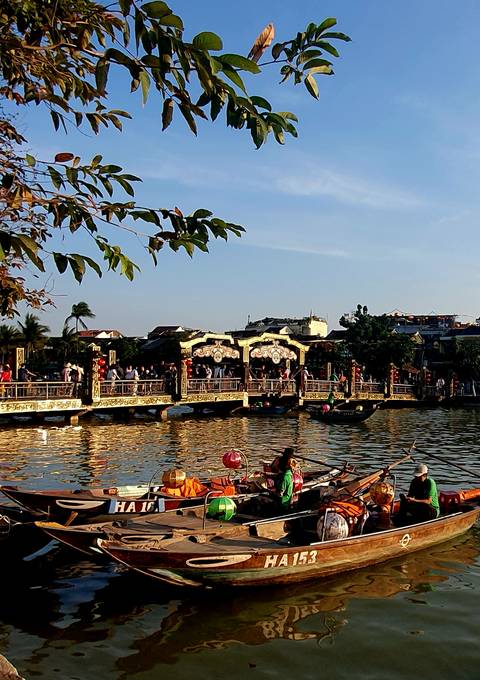 Bridge over a river with many people, decorated with lanterns.