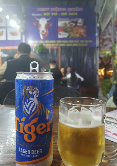 Can of Tiger Asian Lager beer with people in the background.