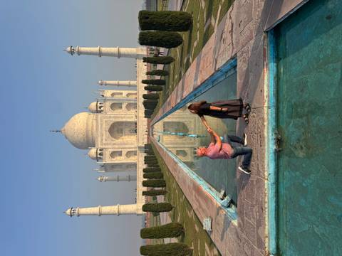 Taj Mahal with a couple posing in front of the reflecting pool.