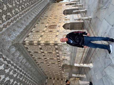       Man standing inside an ornate building with intricate designs.
  