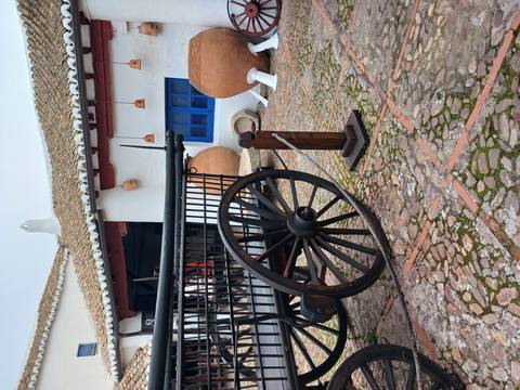 Rustic cart and earthen jars in a historical rural setting.