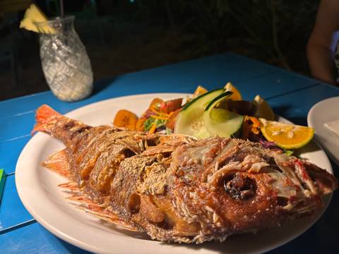 A plate of grilled fish with fresh vegetables in an outdoor setting.