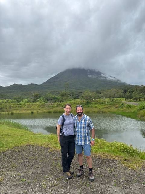Couple posing with a mountain in the background on a cloudy day.