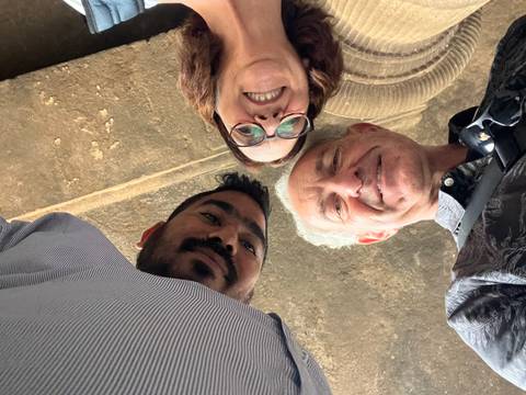 Three people photographed from below with a pillar visible.