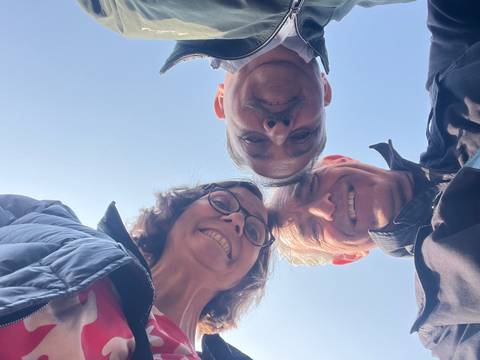 Group of three people looking down at the camera.