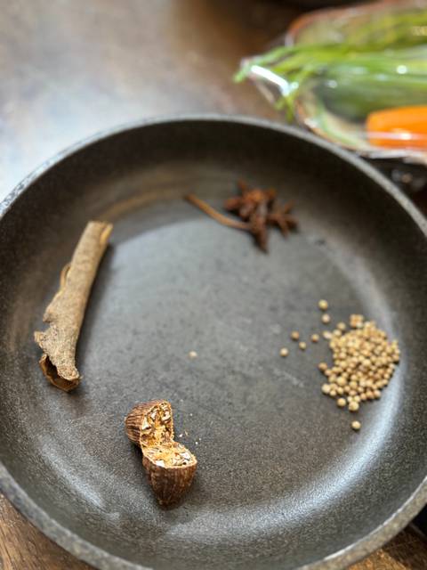 Close-up of spices including star anise and seeds in a bowl.