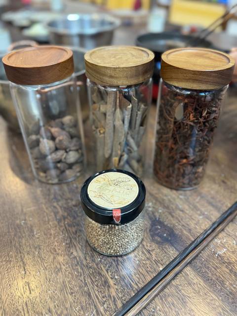       Close-up of jars with spices and herbs on a wooden table.
  