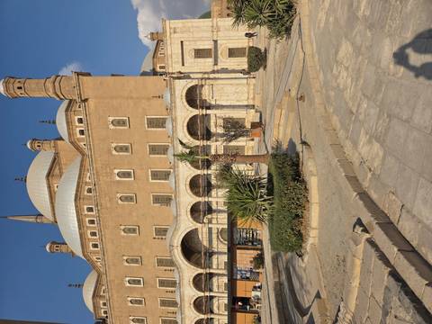 Exterior of a historic mosque with a clear sky and minimal landscaping.