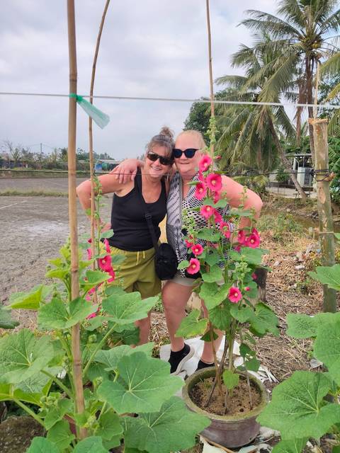 Two women smiling with flower garden in the foreground.