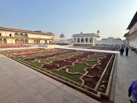 A view of architectural structures with gardens and people walking.