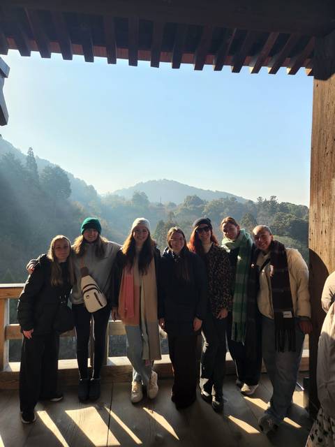       Group of people posing with a scenic mountainous backdrop.
  