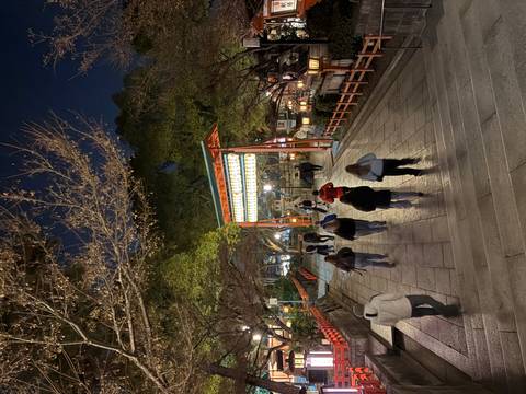 Group of people walking towards a torii gate illuminated at night.