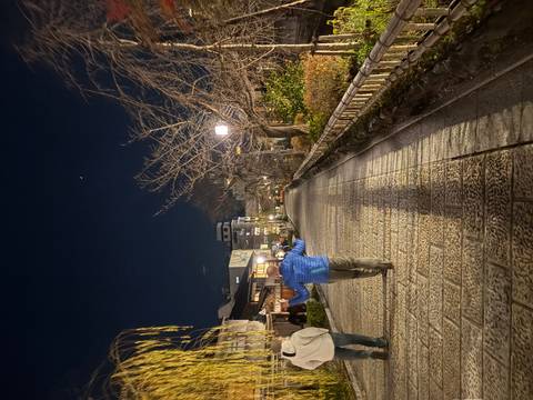 A man walking along a traditional Japanese street at night.