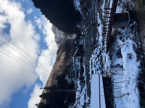       Snowy mountain village with wooden houses under a partly cloudy sky.
  