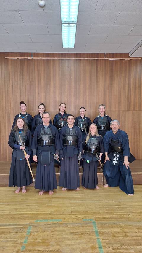       Group of people in kendo armor posing indoors.
  