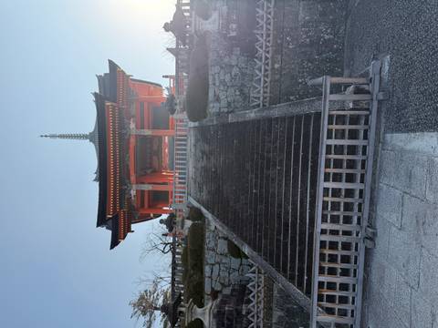 A traditional Japanese temple structure viewed from the bottom of a staircase.
