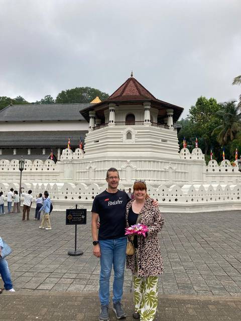 A couple standing in front of a white temple with intricate architecture.