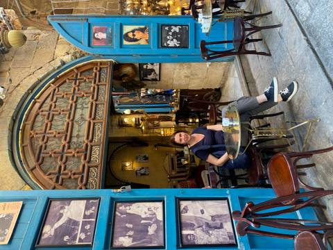       A woman sitting at a quaint café with classic décor.
  