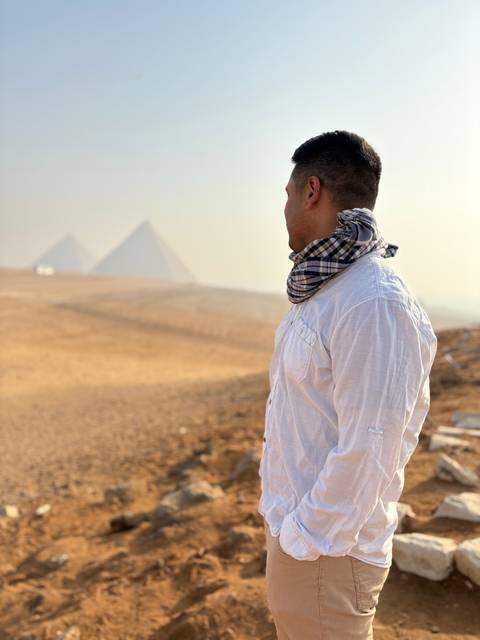      Man with scarf looking towards pyramids
  