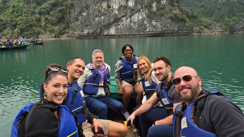 A group of people on a boat tour with life vests near rocky cliffs.
