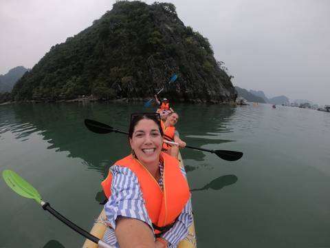 People kayaking on calm waters with scenic cliffs.