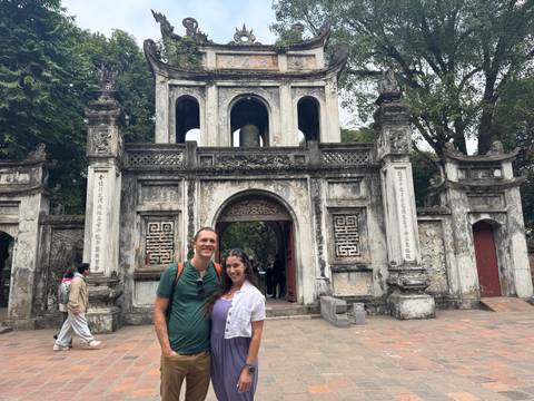 A couple posing in front of an ancient stone gate with intricate carvings.