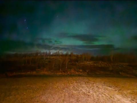 Night sky with faint auroras visible over a barren landscape.