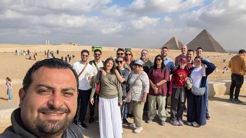 Tour group with pyramids and desert landscape in the background.