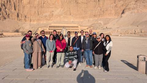 Tour group in front of an ancient Egyptian temple under a bright sky.