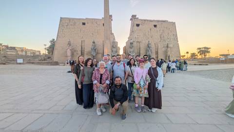 Tour group posing at the entrance to an ancient temple at sunset.