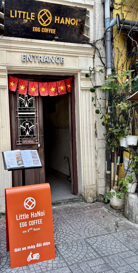 Entrance to a building with a menu displayed outside and green plants.