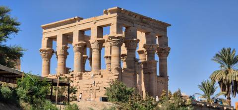       Ancient ruins of a temple with intricate columns and greenery.
  
