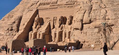       Abu Simbel temples with many tourists exploring the ancient site.
  
