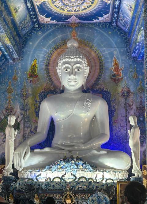 Large white Buddha statue with a colorful mural background.