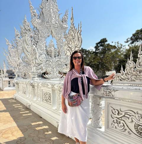 A woman posing in front of ornate white architecture.