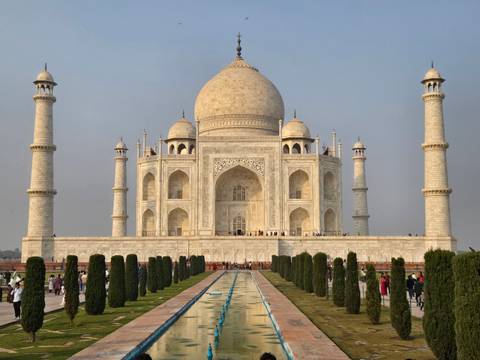 Taj Mahal with domes and minarets against a slightly hazy sky.