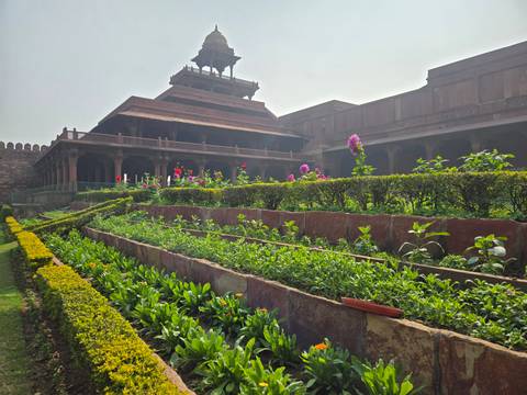 Gardens at a historical site with a large structure in the background.