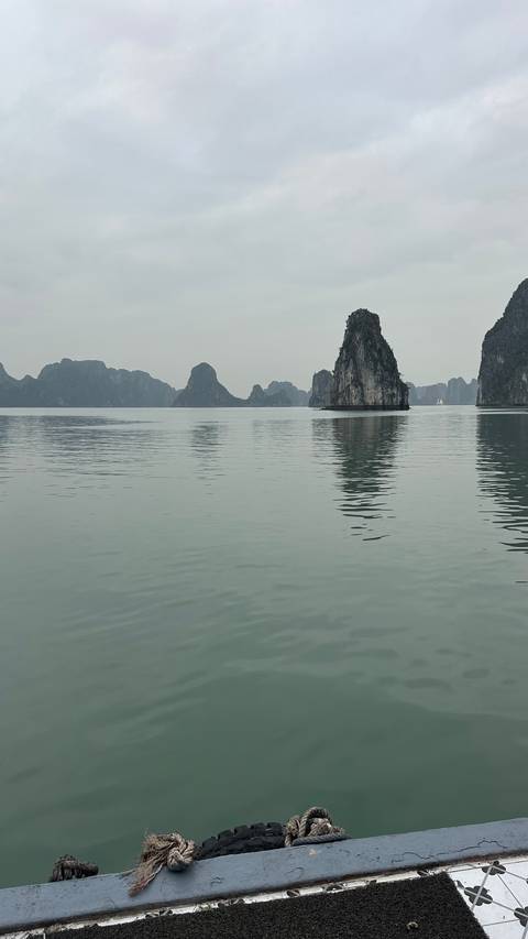       Karst limestone formations reflected in calm water, typical of Halong Bay.
  