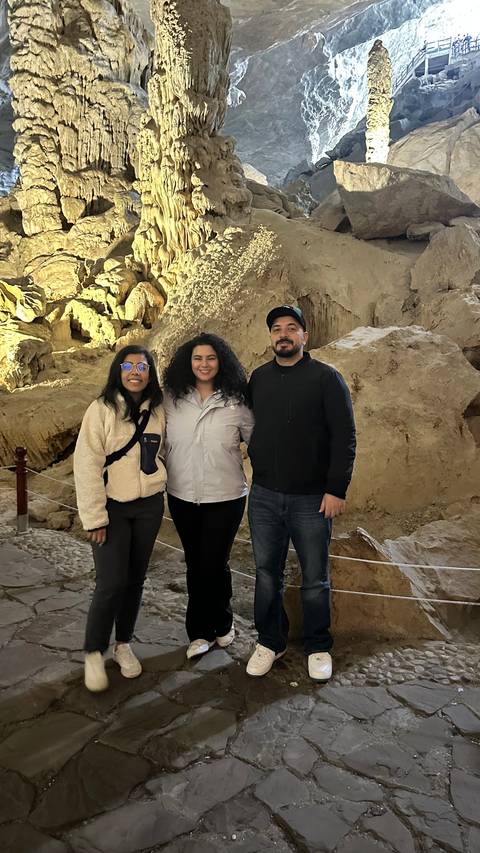       A group of people posing inside a cave with rock formations.
  